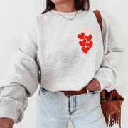 Person wearing a gray sweatshirt with a red heart design, 1 in 6