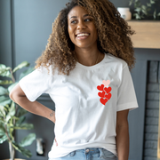 Woman wearing a white t-shirt featuring a small stacked 1 in 6 heart design in red and pink on the left chest.
