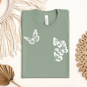 Sage green t-shirt with white butterfly designs on a light background white butterflies symbolizing the 1 in 4 miscarriage statistic.
