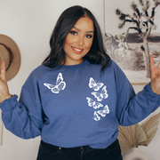Woman wearing an indigo blue crewneck with six white butterflies symbolizing the 1 in 6 infertility statistic.