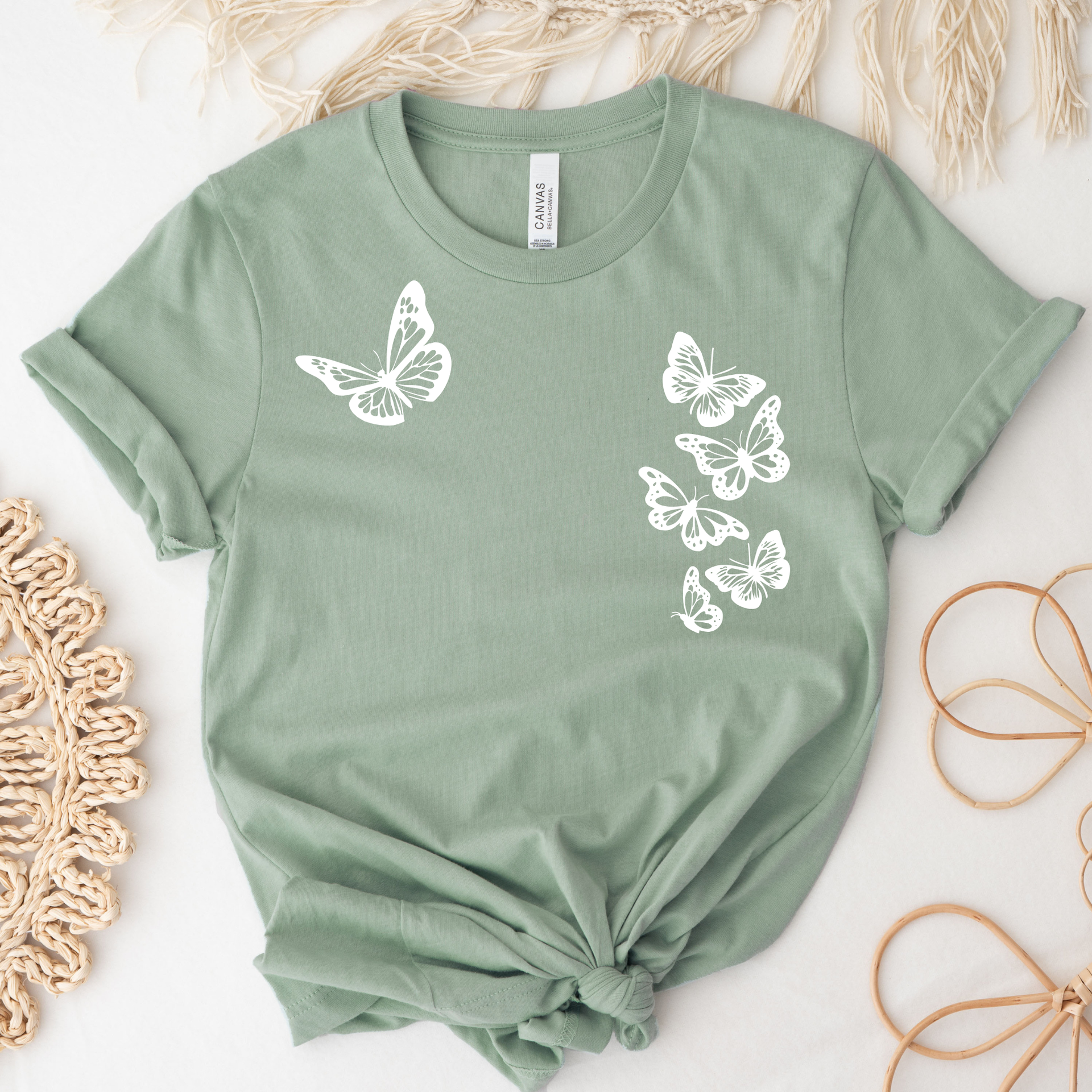 SAGE green tee with six white butterflies symbolizing the 1 in 6 infertility statistic.