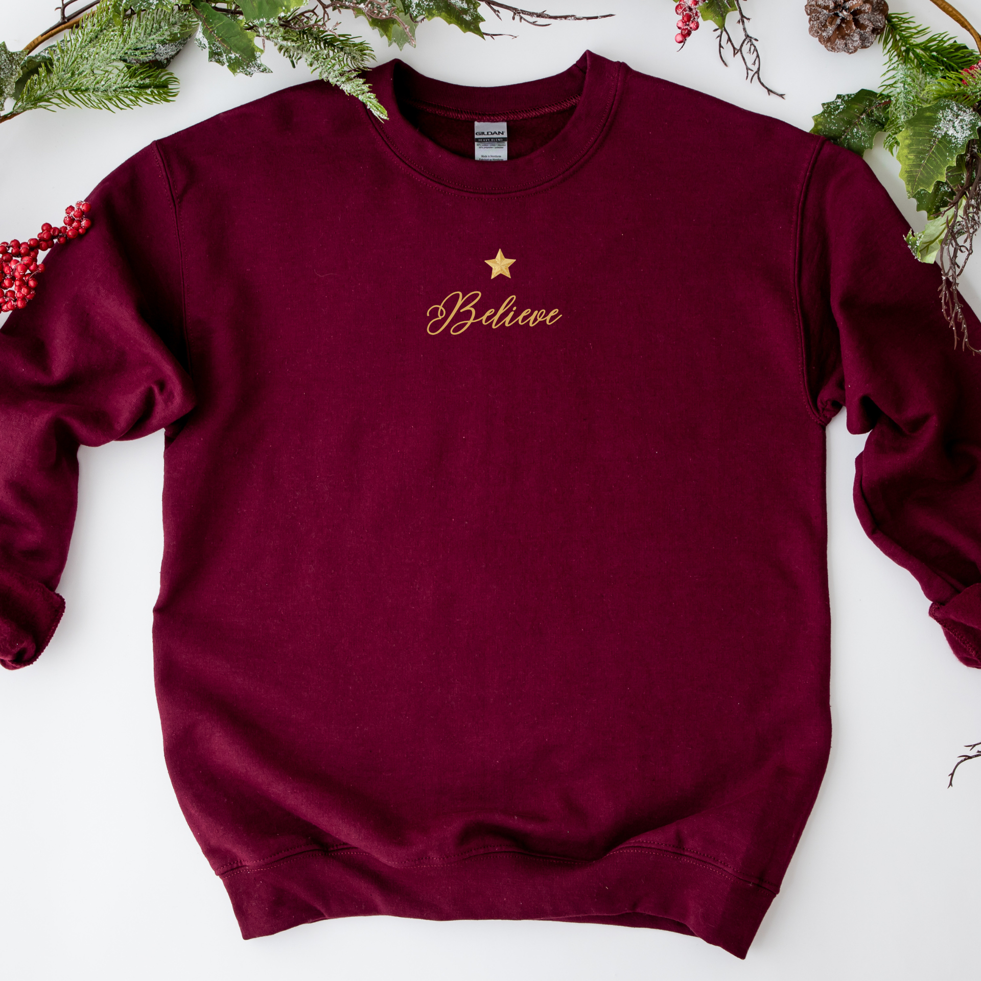 Maroon sweatshirt with 'Believe' and a star on a white background