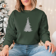Person wearing a green sweatshirt with a Christmas tree design in front of a decorated Christmas tree.