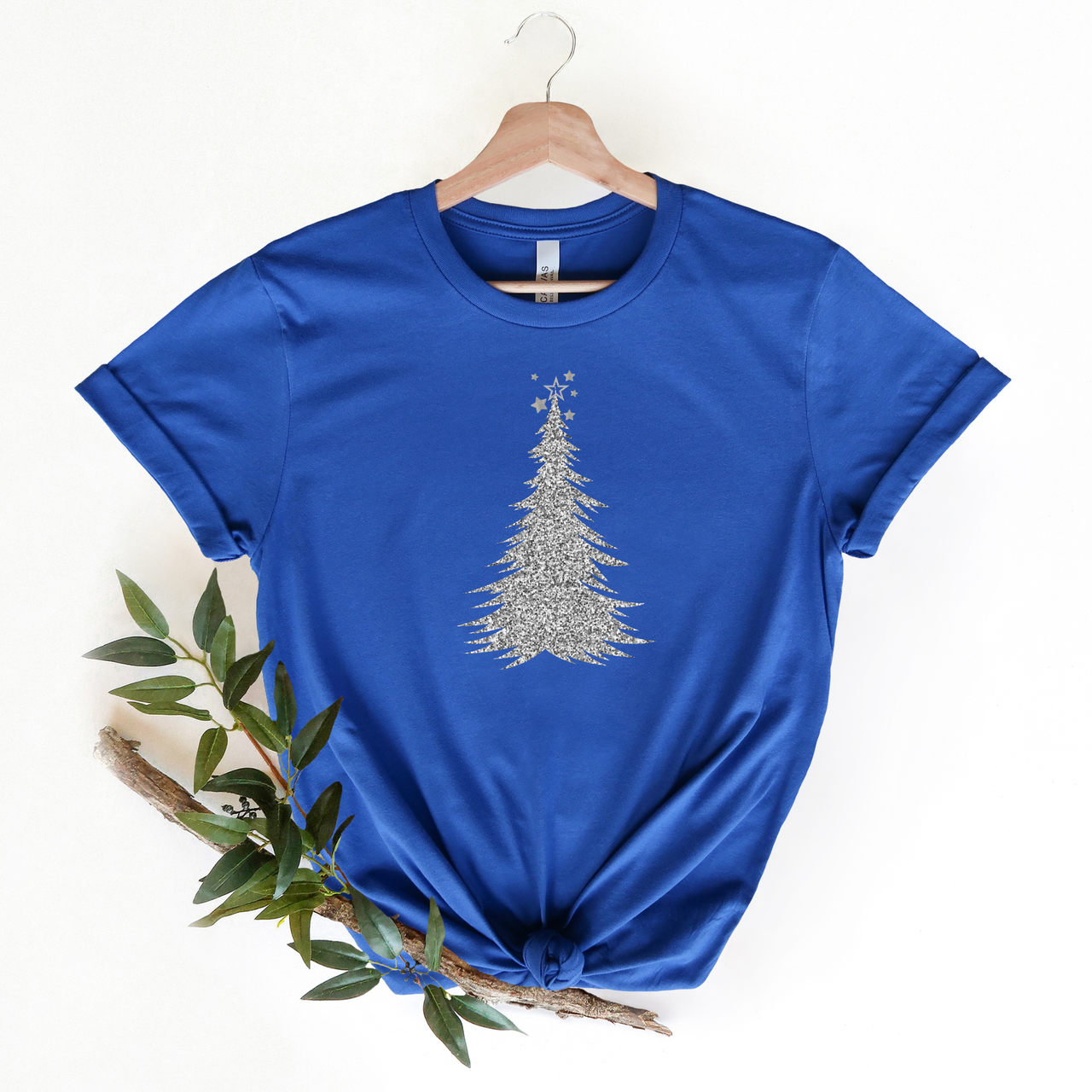 Blue t-shirt with a silver tree design on a hanger against a white background